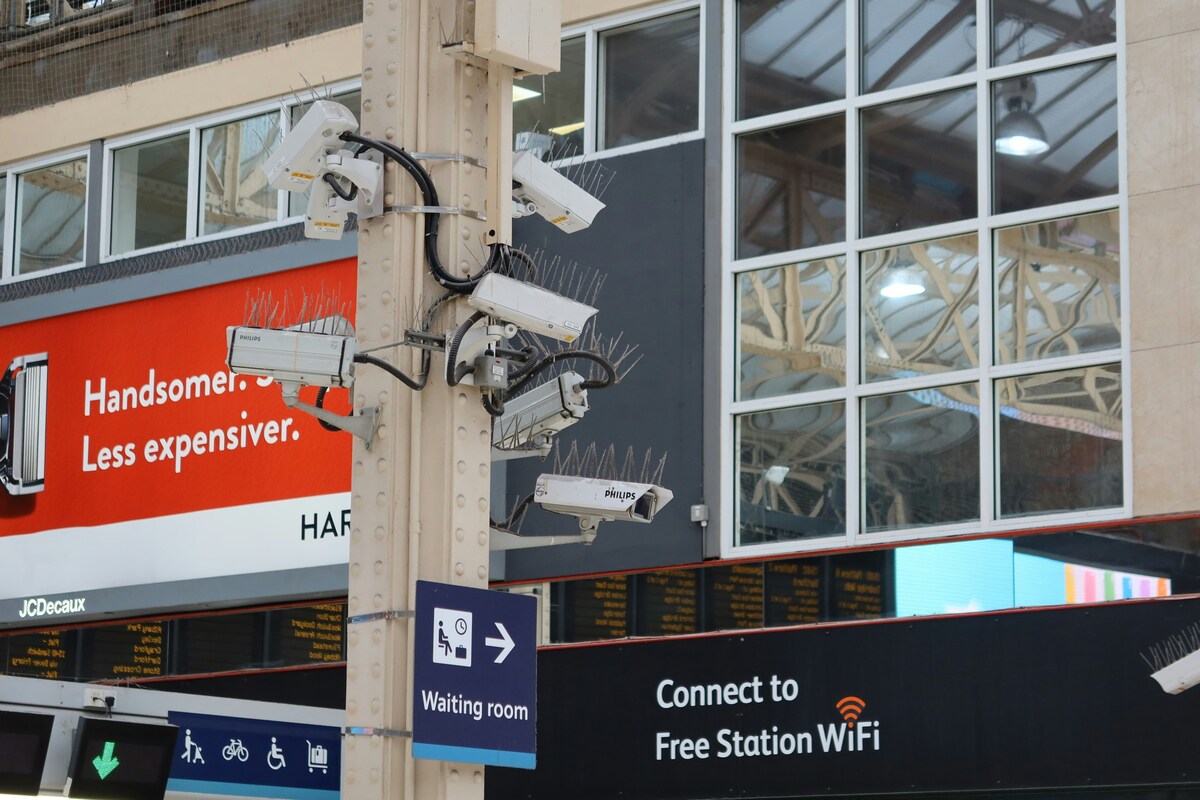 Several CCTV cameras mounted on a pole outside a building, pointing in different directions.