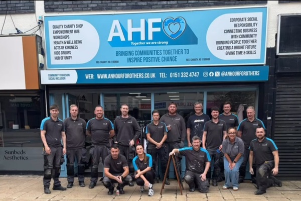 Group of corporate volunteers outside the office of An Hour for Others with bright blue signage