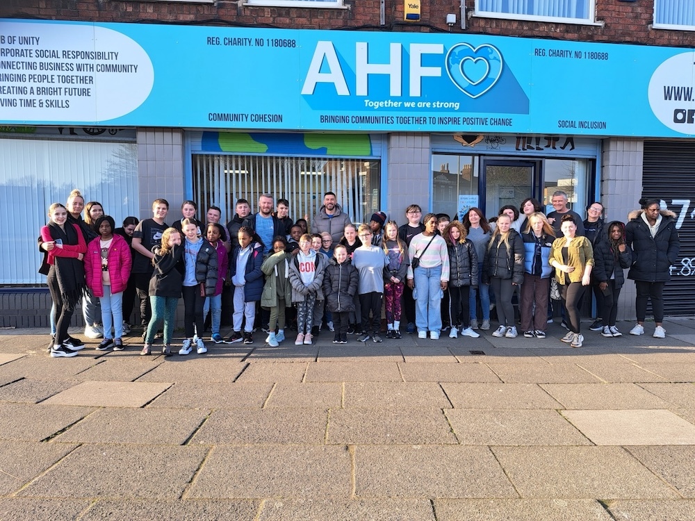 Group of children and young people outside an office in Liverpool with blue signage