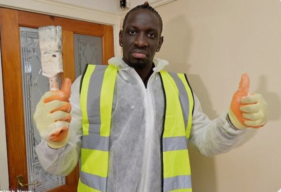 Man standing in room wearing a high vis jacket holding a paint brush