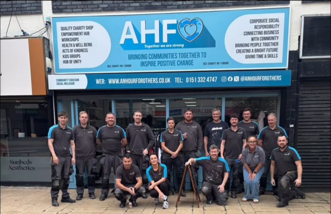 Group of corporate volunteers outside the office of An Hour for Others with bright blue signage