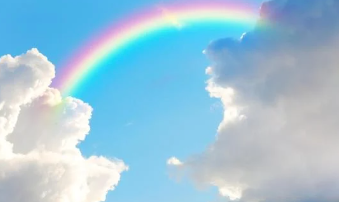 blue sky with rainbow and white puffy clouds