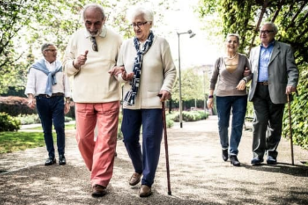 people walking and a couple using a cane