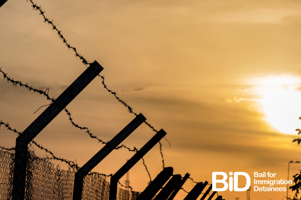 Picture of barbed wire silhouetted against an orange sunset. 
