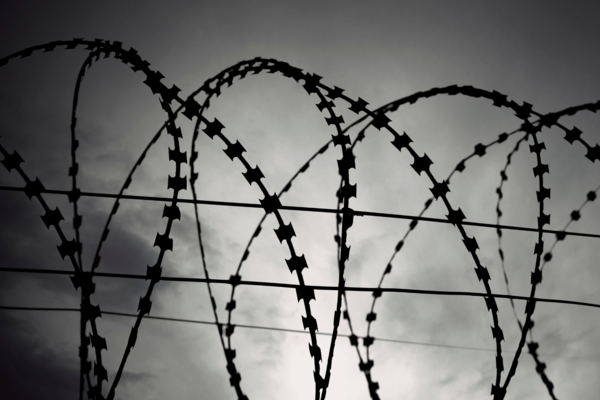 Black and white image of barbed wire against a great sky