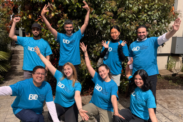 8 Individuals stand in blue BID t-shirts smiling with their arms out whilst surrounded by greenery, celebrating their participation in the walk. 