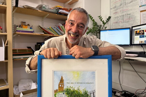 Pierre smiles with a painting presenting his journey at BID.