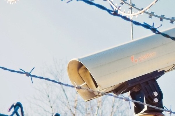 image of prison security camera behind barbed wired pointing downwards