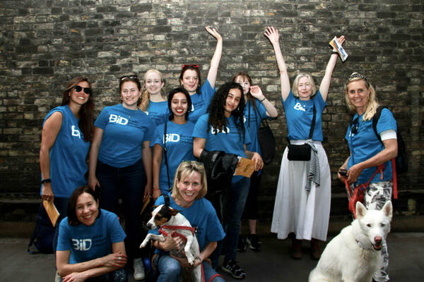 Image is of 12 people and two dogs in blue t-shirts with BID's logo on it
