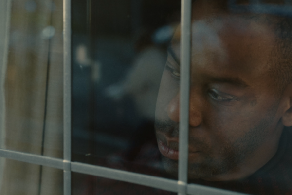 man with sad expression looking out of window 