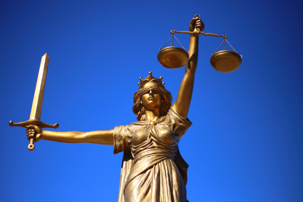 statue of Lady Justice holding scales against blue sky