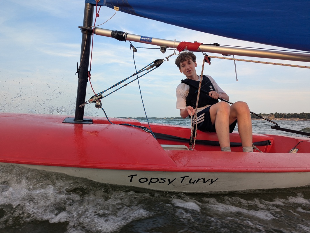 Child sailing a red sailing dinghy