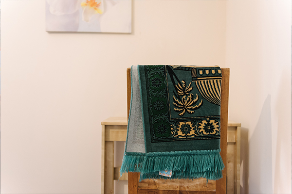 A yellow and teal scarf hung over the back of a chair next to a table in a house.
