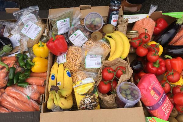 A table laden with fruit and vegetables and lots of bags of donated groceries