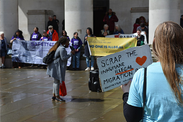 A woman holding a sign saying 'scrap the inhumane Illegal Migration Bill'
