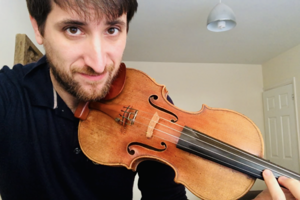 Guillem Calvo smiling into the camera with his violin