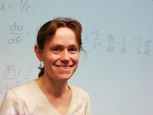Photo of Helen Wilson in front of a whiteboard showing mathematics