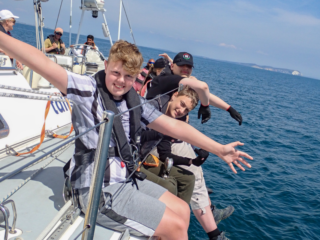 a group of young people sat on the side of a tall ship