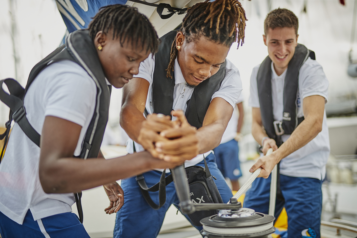 Three young people shown winching on a tall ship