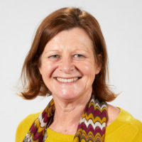 Sue Elder - a lady with mid length brown hair wearing a yellow top