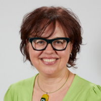 Nicky Everett - a lady with short auburn hair and glasses wearing a green top