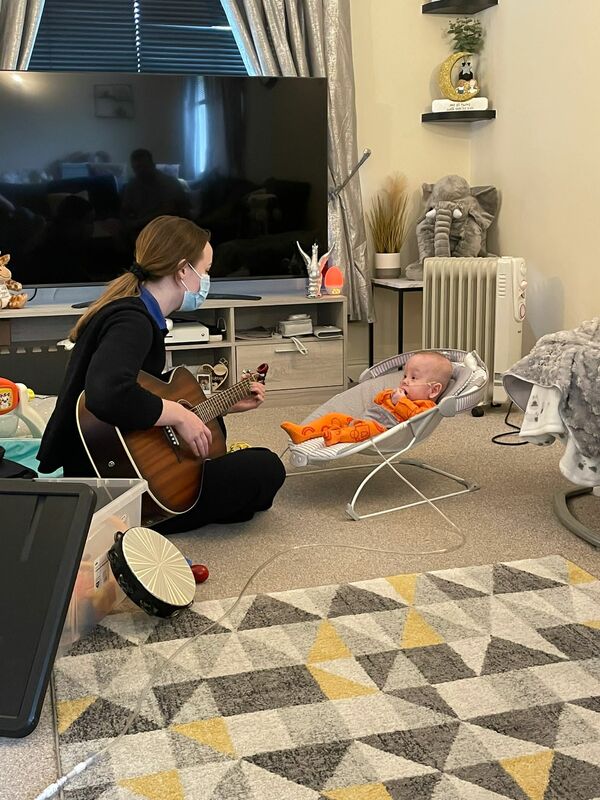 A woman playing guitar to a baby.