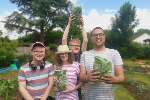 A group of young beneficiaries proudly hold up cabbages they have grown.