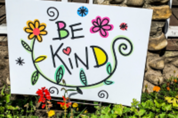Artwork with the words 'Be Kind' with flowers and leaves around the painting in yellow, pink and green
