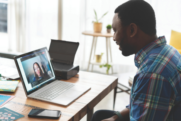 A black man sits talking to someone on facetime on a laptop