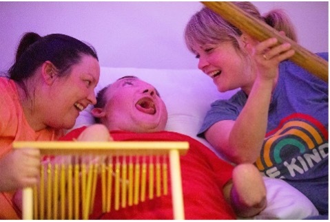 Two care workers doing musical therapy with a disabled child