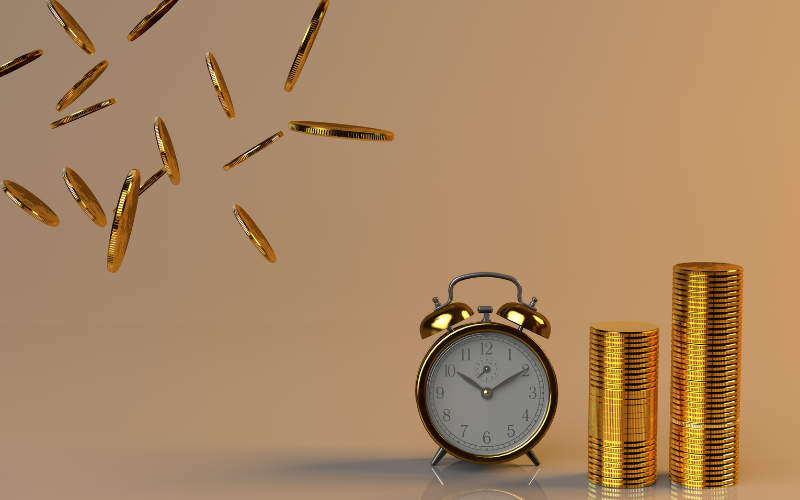 A clock with a pile of coins and some nearby flying in the air