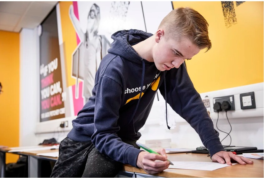Young man sitting on a table and writing on a piece of paper