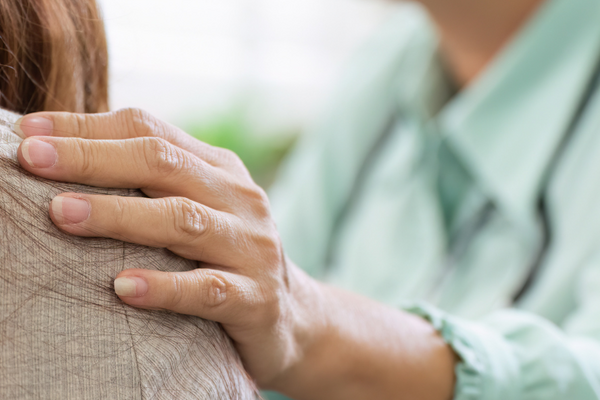 A volunteer placing a hand on another persons shoulder