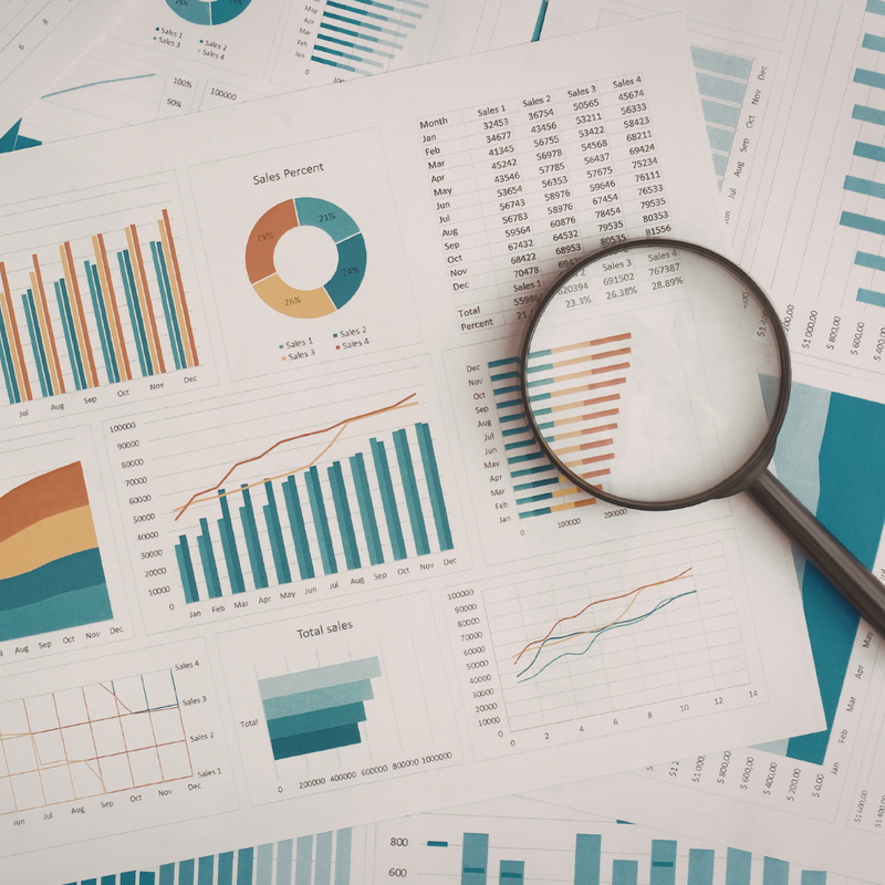 A magnifying glass laid over papers showing data and graphs