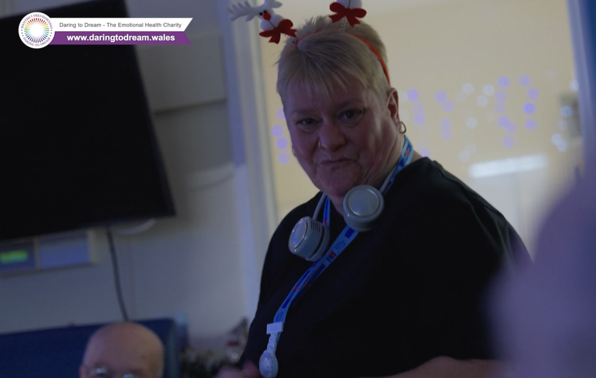 A lady looks towards the camera smiling with festive headwear on.