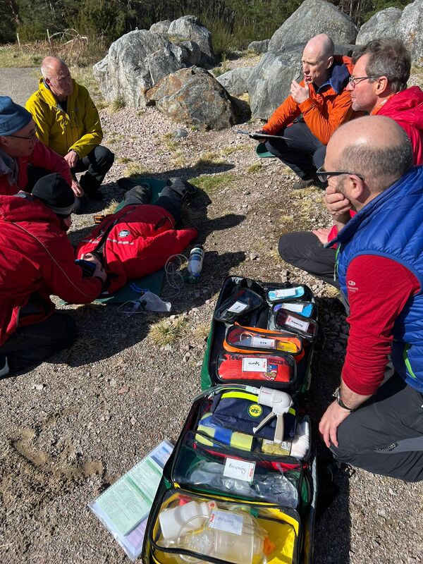 Mountain rescue team knelt down supporting person in need