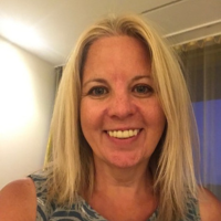 A head and shoulder photo of a lady with shoulder length blonde hair, smiling at the camera