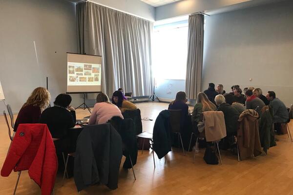 Image of a group of people sat round tables looking at a presenation