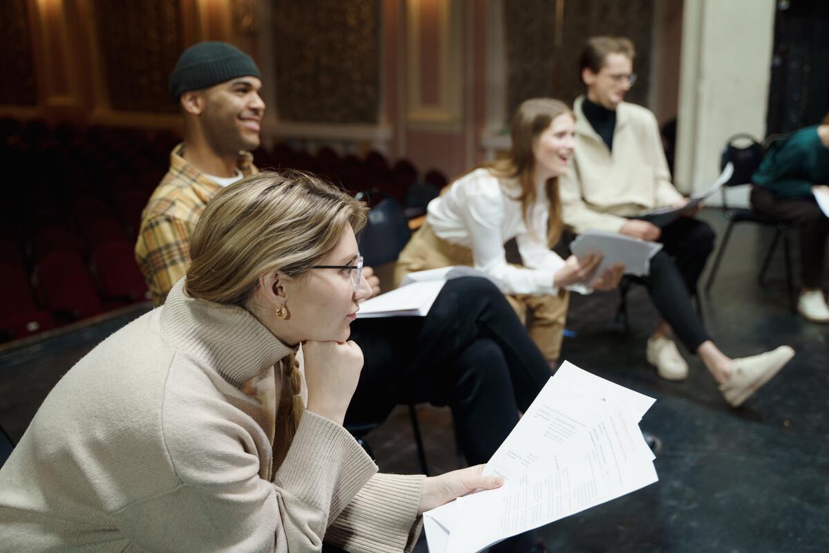 People sat round a stage with scripts in their hands