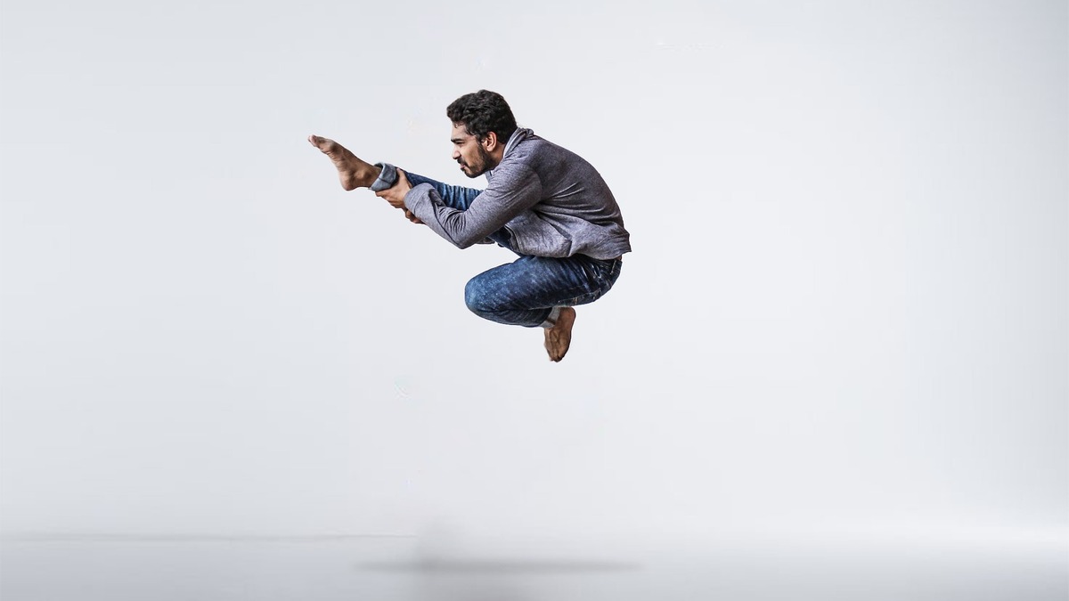 A man jumping in the air holding his leg whilst dancing