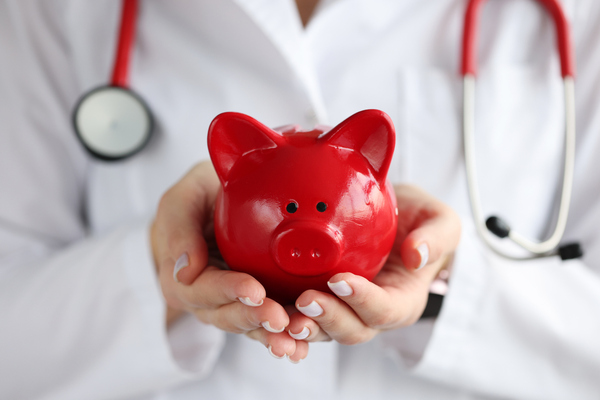 Picture of a doctor holding a red piggy bank 