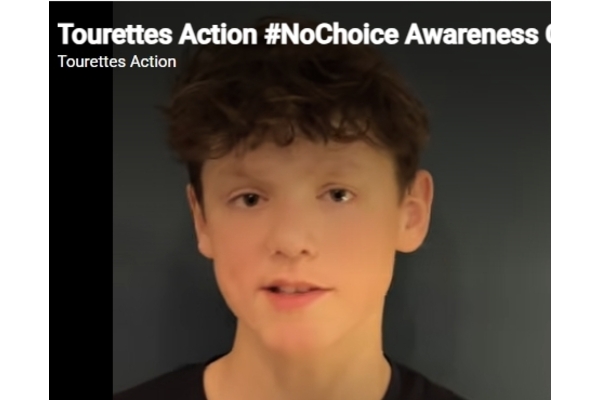 Photo of a teenager talking about his experience of Tourettes, with the video captions above his head saying: Tourettes Action #NoChoice Awareness by Tourettes Action