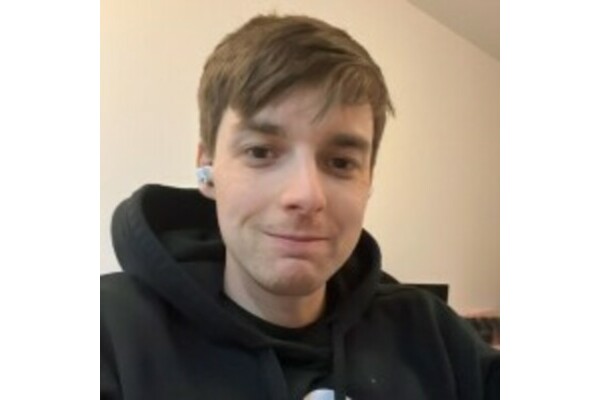 a photo of Ali smiling wearing a black hoodie 