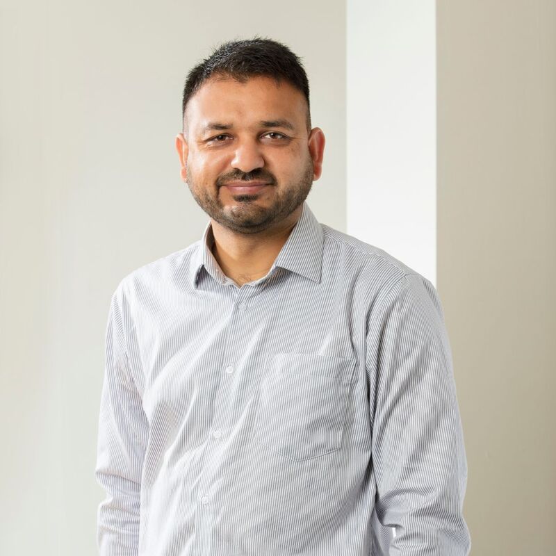 Asjad smiling wearing a grey shirt