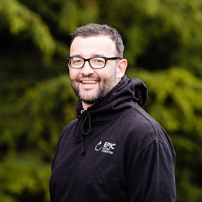 Richie smiling at the camera wearing an EPIC Restart hoodie