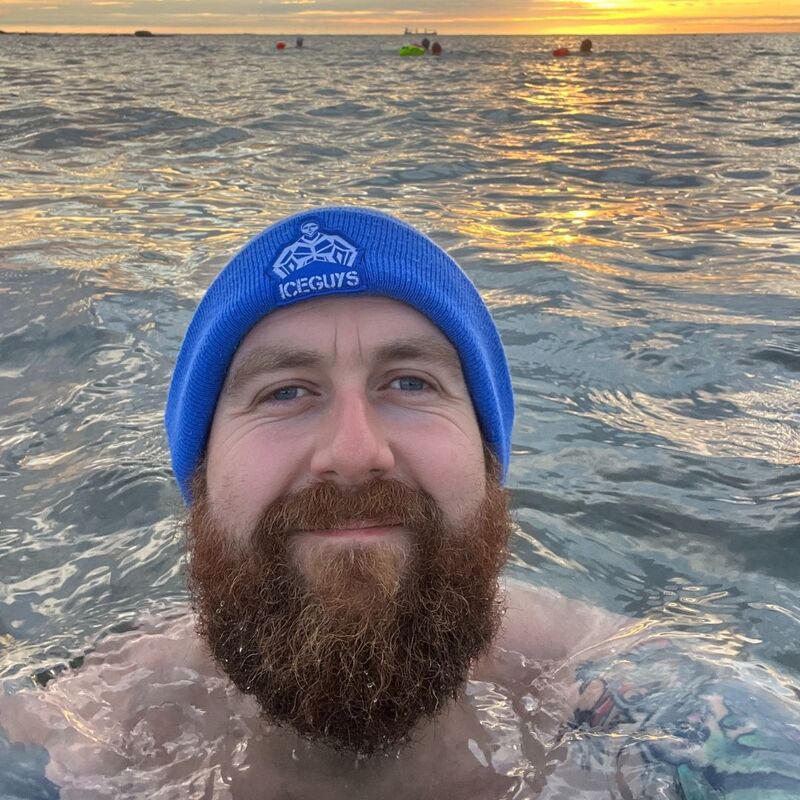 Craig swiming in the sea wearing a blue hat with the ICE Guys logo on the front