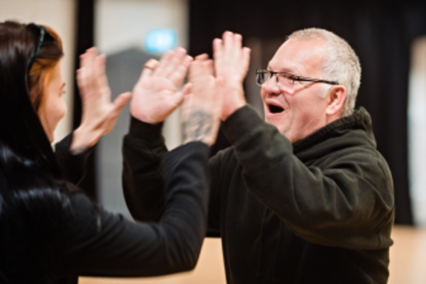 A woman and a man smiling and clapping hands