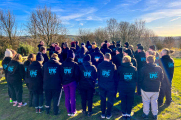 A group of people who are attending an EPIC Restart event stood with their backs to the camera wearing EPIC Restart hoodies