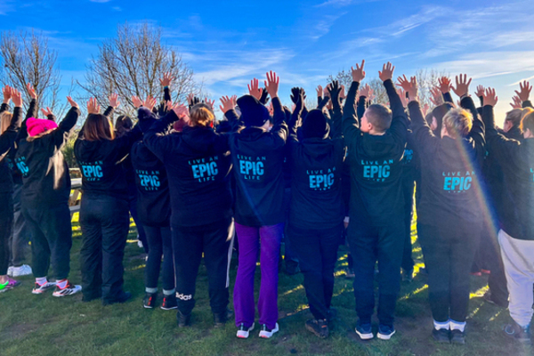 A group of people wearing EPIC Restart hoodies, with their arms in the air