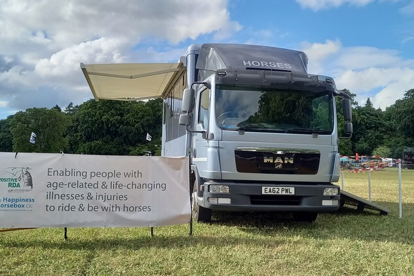 Front shot of the Happiness Horsebox with its awning out and a banner explaining its role.